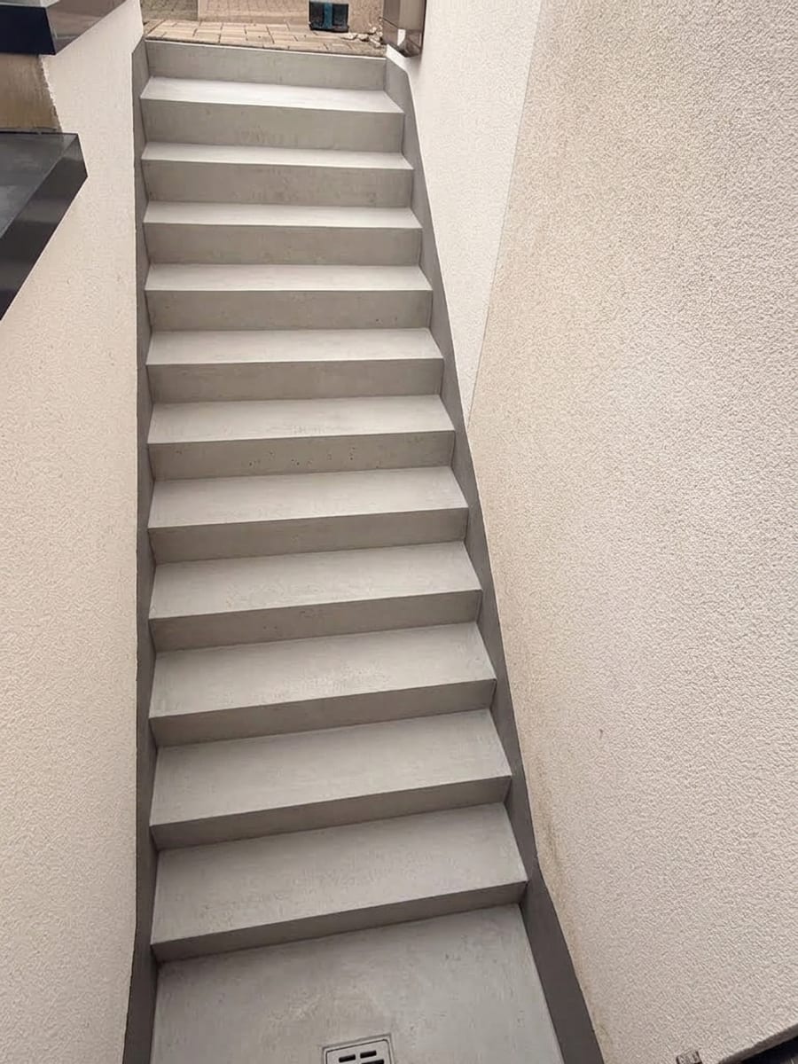Schmale Betontreppe zwischen zwei Hauswänden vor der Beschichtung